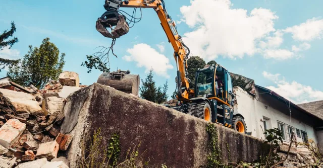 A bulldozer efficiently demolishing an old building, clearing rubble.