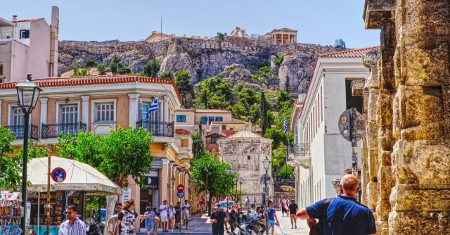 Bustling street in Athens with a view of the Acropolis, capturing local life and historic architecture.