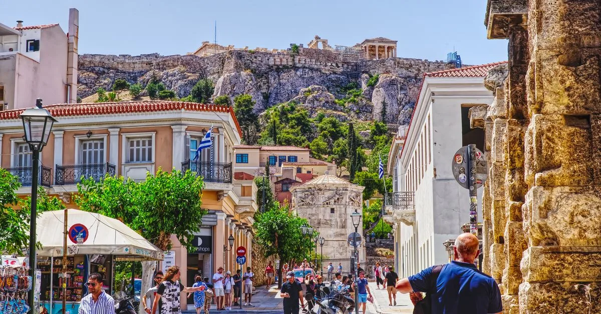 Bustling street in Athens with a view of the Acropolis, capturing local life and historic architecture.