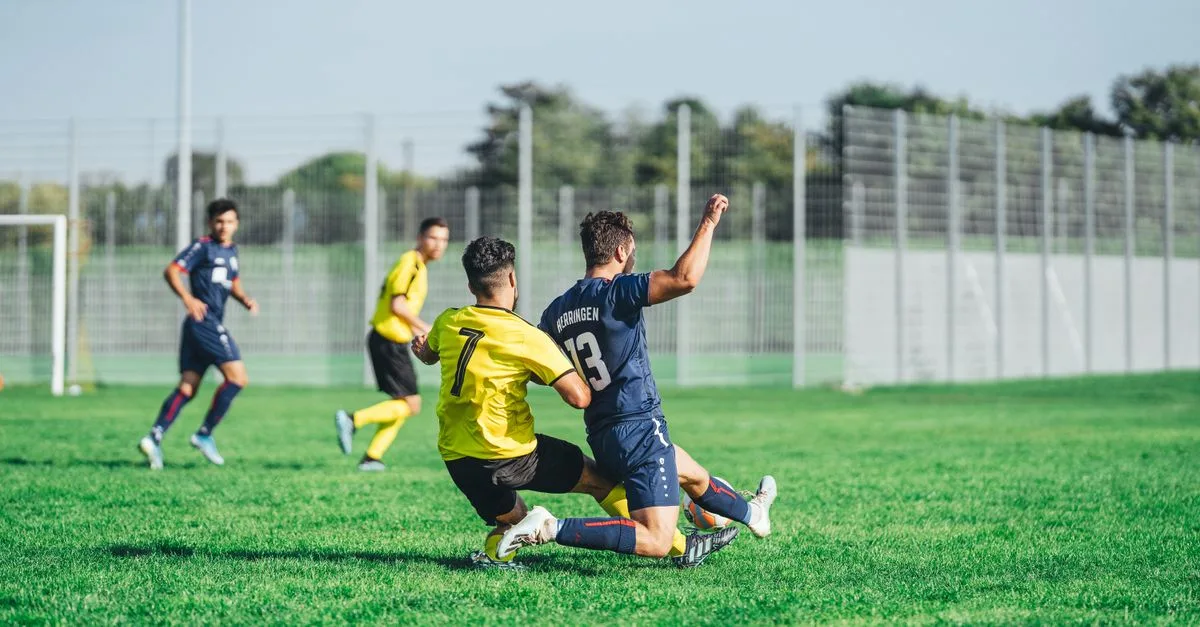 Soccer players in action during a competitive match on a sunny day outdoors.