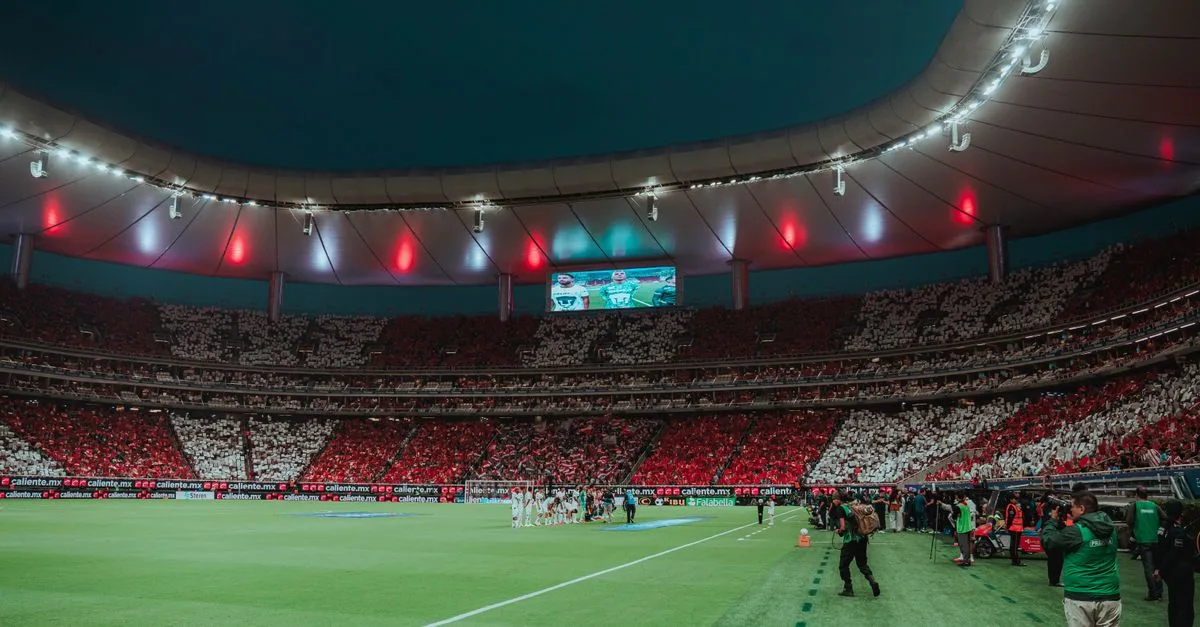 A soccer stadium at night with colorful crowd displays and energetic atmosphere.
