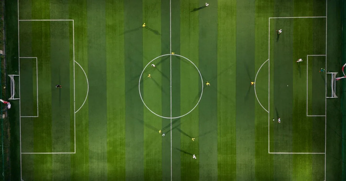 Dynamic aerial shot capturing a soccer match on a vibrant green field at night.