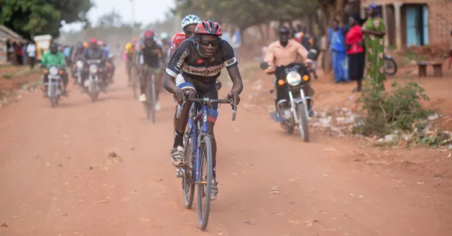 A thrilling cycling race unfolds on a dirt road in Africa, capturing the essence of competition and endurance.