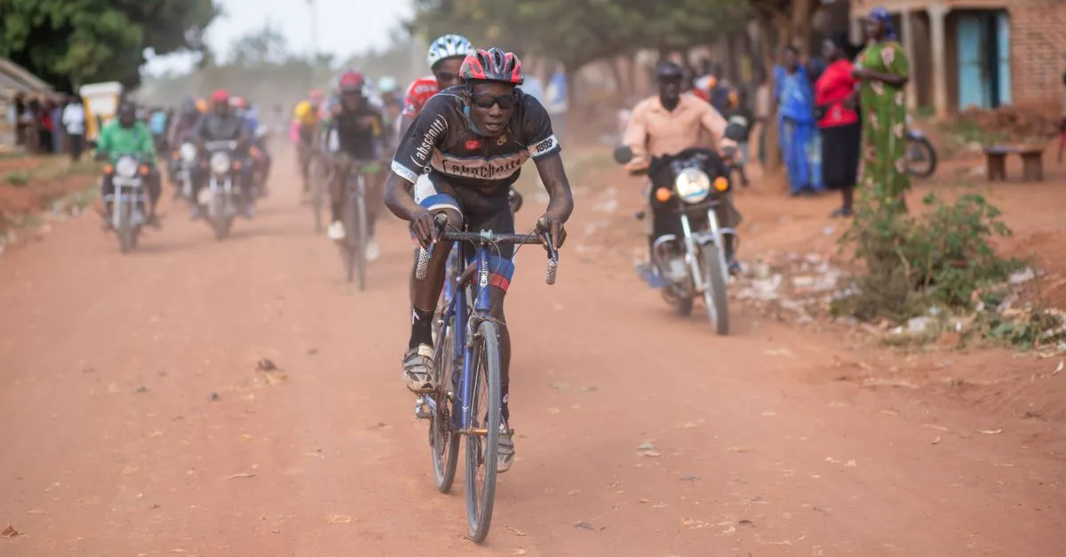A thrilling cycling race unfolds on a dirt road in Africa, capturing the essence of competition and endurance.