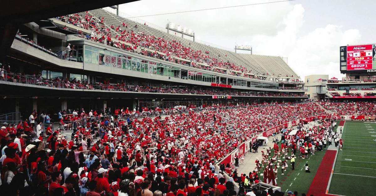 A vibrant crowd in a stadium cheering during an outdoor football game, creating an energetic atmosphere.