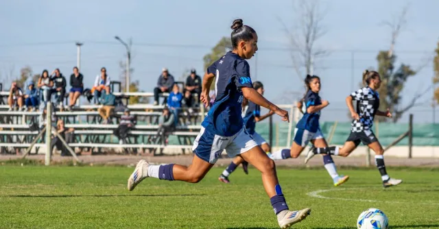A woman dribbles the ball during a daytime soccer match, showcasing athletic skill and teamwork.