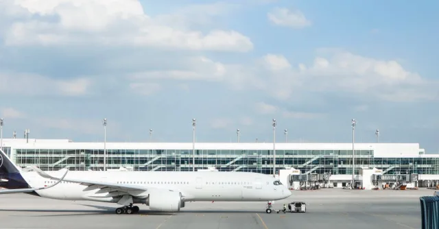 Widebody aircraft parked at an airport gate during clear day with terminal building visible.