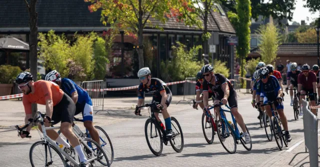 Adult men cycling in a competitive street race under sunny skies.