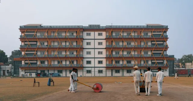 Young cricketers prepare the field in front of a building in Delhi, India.