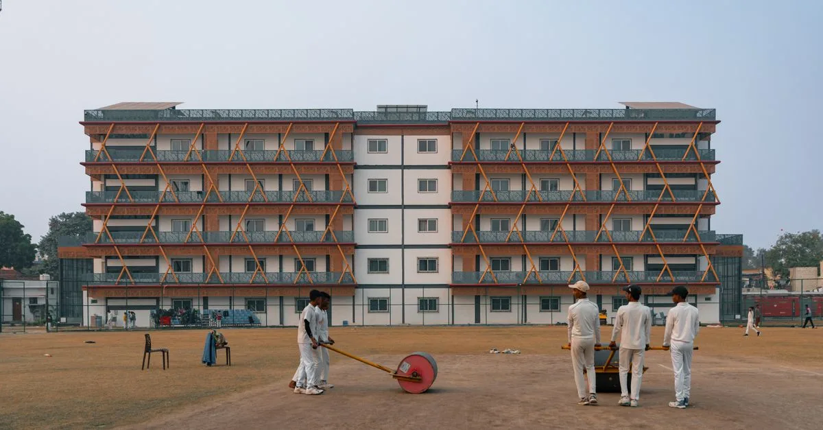 Young cricketers prepare the field in front of a building in Delhi, India.