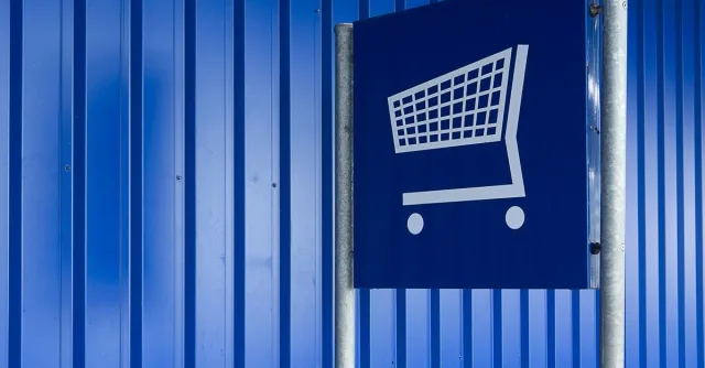 Blue metal wall with a shopping cart sign symbolizing retail or supermarket area.