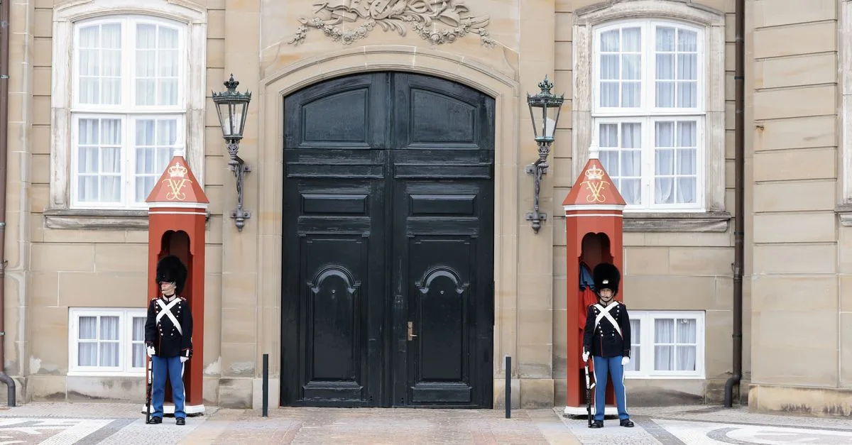Two Royal Guards stand solemnly at Amalienborg Palace entrance in Copenhagen, Denmark.