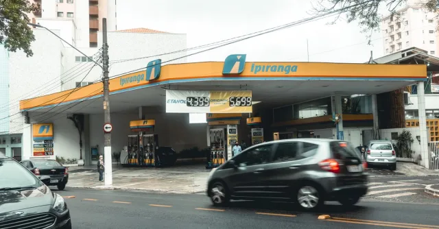 Ipiranga gas station with moving vehicles on a bustling city street.