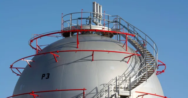 Close-up view of a large industrial gas storage sphere with a surrounding metal staircase.