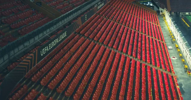 Rows of empty red seats in a UEFA Europa League stadium, captured from above.
