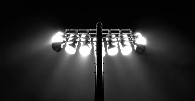 Black and white photo of stadium floodlights illuminating the night sky in Boston.