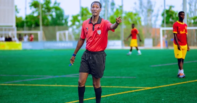 Soccer referee in action on field during a match, guiding players.
