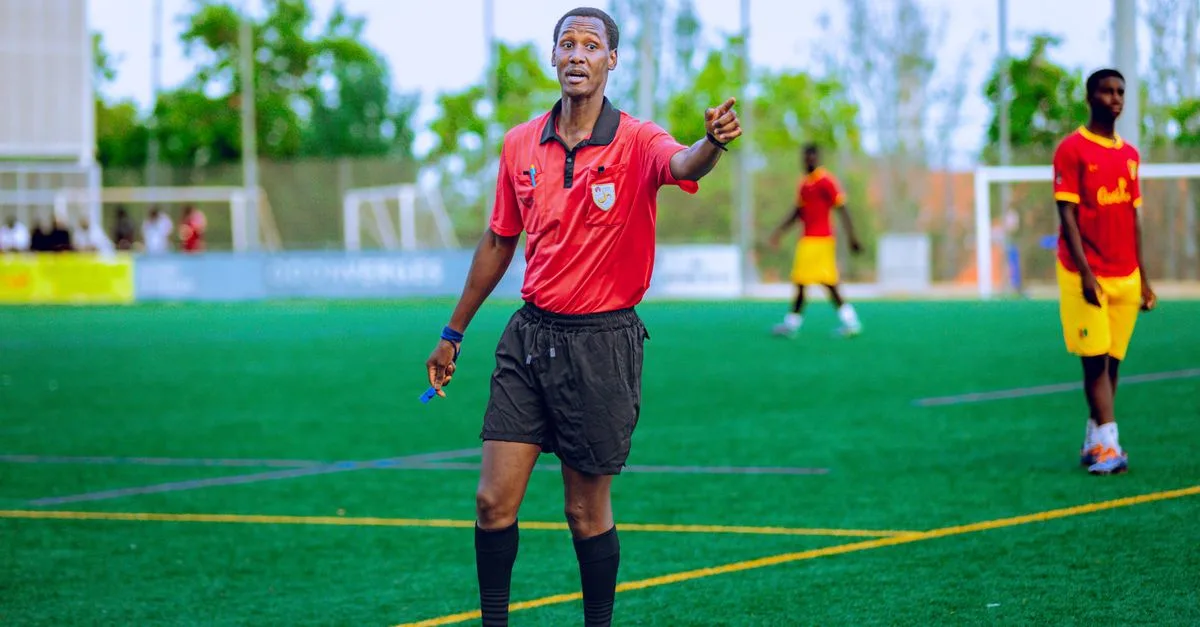Soccer referee in action on field during a match, guiding players.