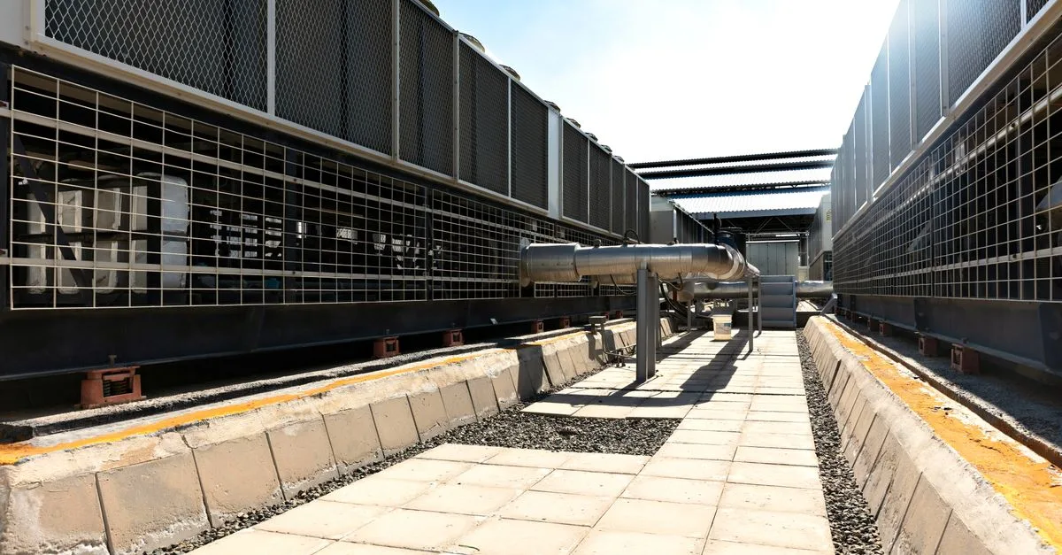 View of a large industrial cooling system with metal pipes and grids outdoors under bright daylight.