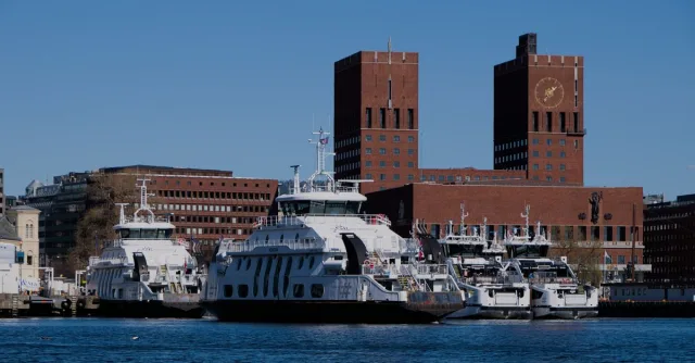 Ferries and Oslo City Hall under a clear blue sky. Perfect urban waterfront scene.