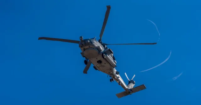 A military helicopter in flight against a clear blue sky in Los Llanos, Spain.