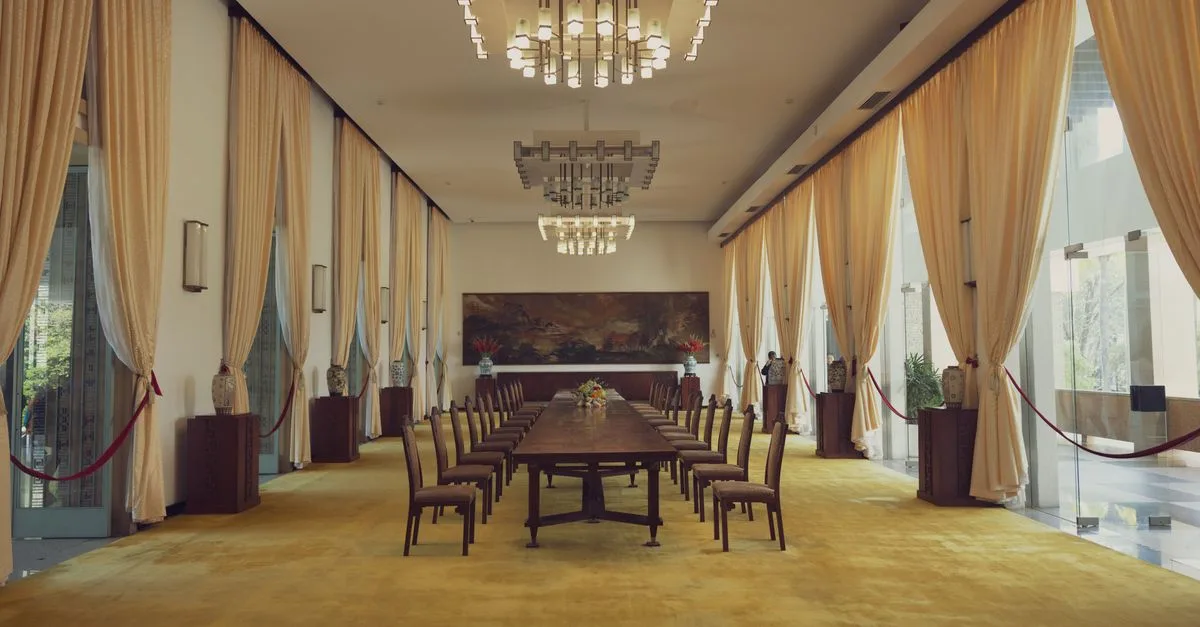 Spacious banquet room with luxury decor in Reunification Palace, featuring elegant chandeliers and long dining table.