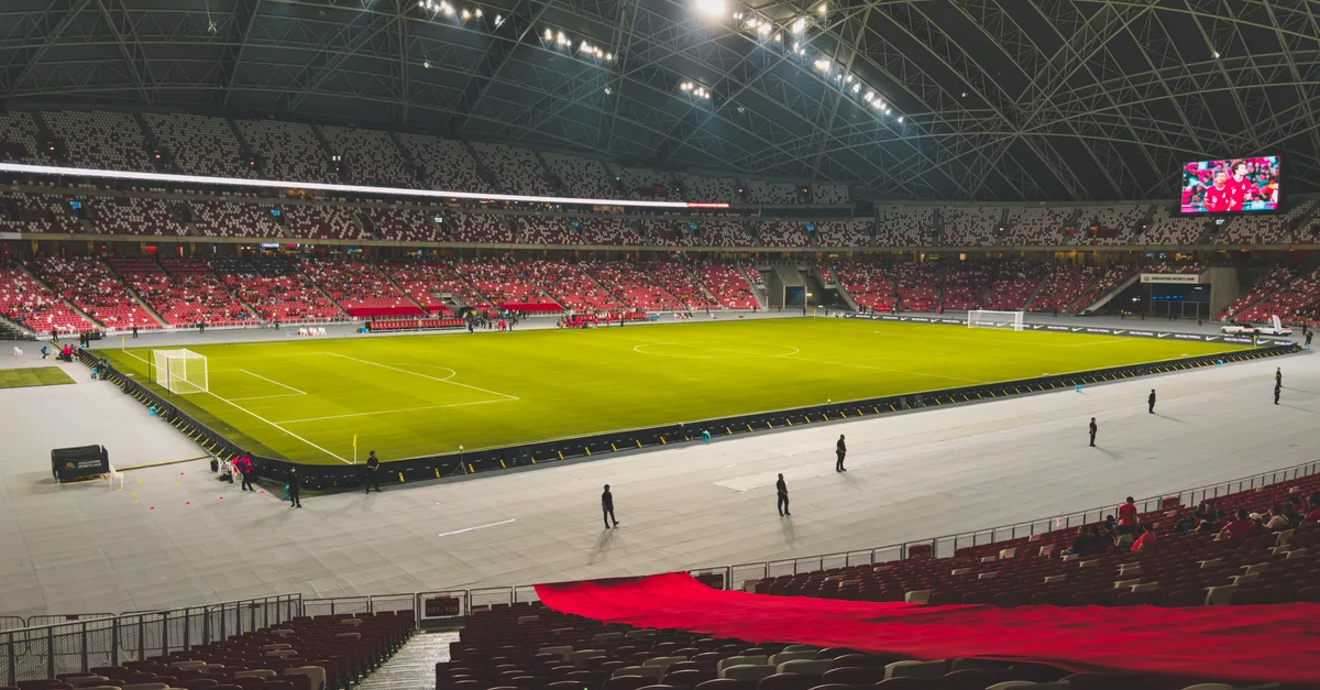 Spacious indoor soccer stadium with green field and illuminated seating area.