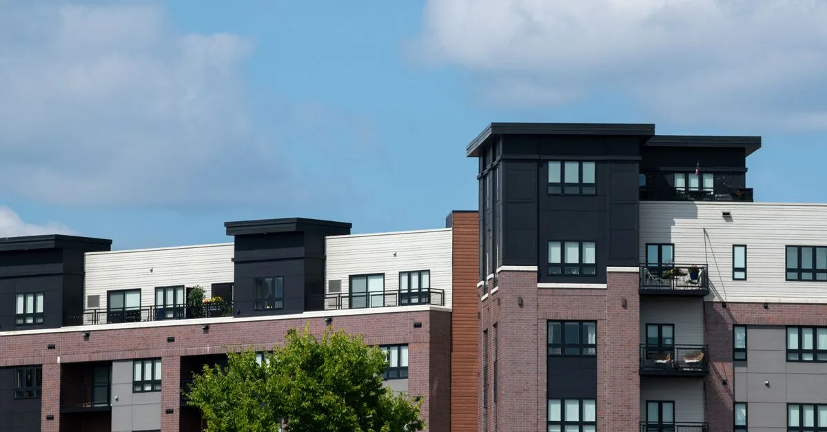 Contemporary urban apartment complex with brick and panel design under clear blue skies.