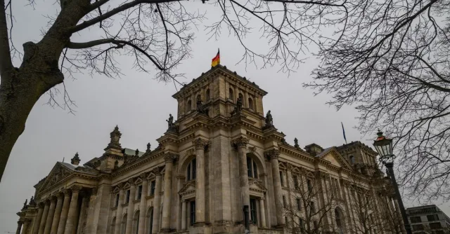 View of the iconic Reichstag building in Berlin, Germany, framed by bare winter trees.