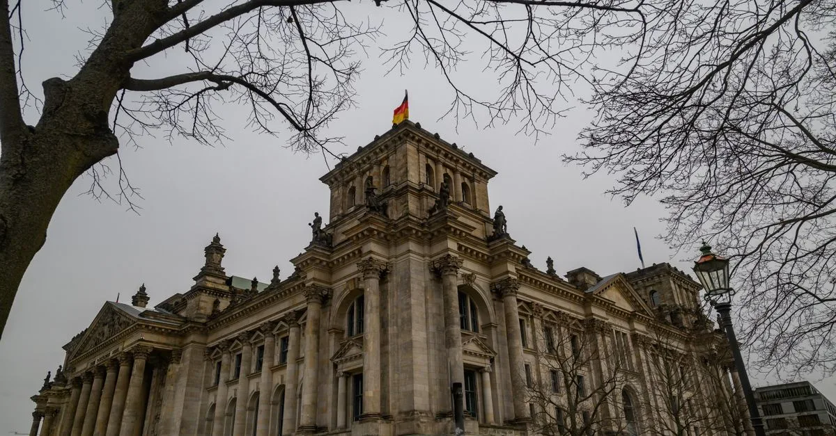 View of the iconic Reichstag building in Berlin, Germany, framed by bare winter trees.