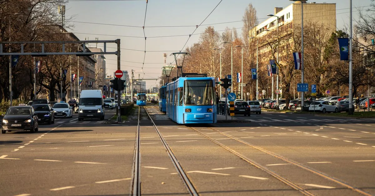 Blue tram traversing a busy street in Zagreb, Croatia's urban landscape.