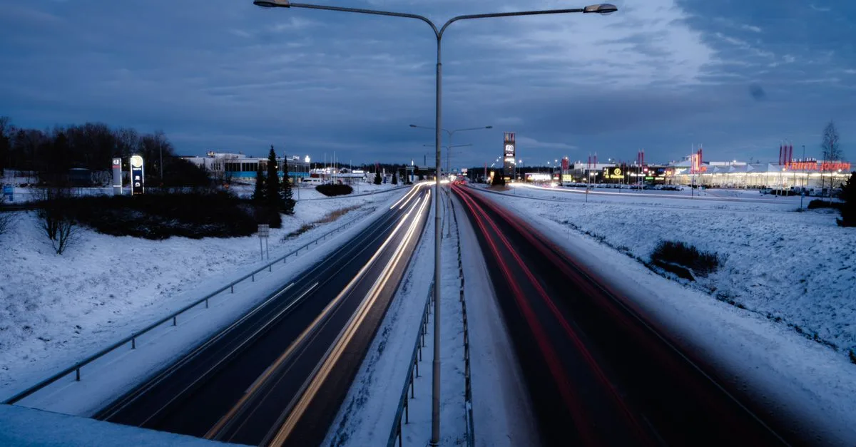 Long exposure of car light trails on a snowy highway in Raisio, Finland during winter evening.