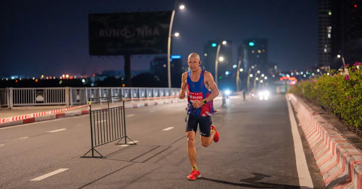 A focused runner competes in an urban marathon at night, road illuminated by streetlights.