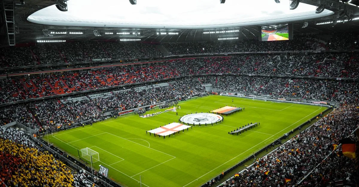 A vibrant soccer stadium filled with fans watching a game, flags displayed on the field.