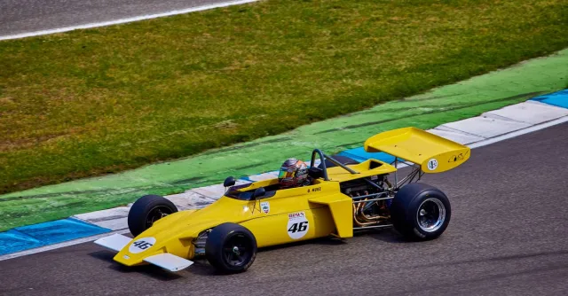 Vibrant yellow vintage race car speeding on a race track, capturing the essence of motorsport.