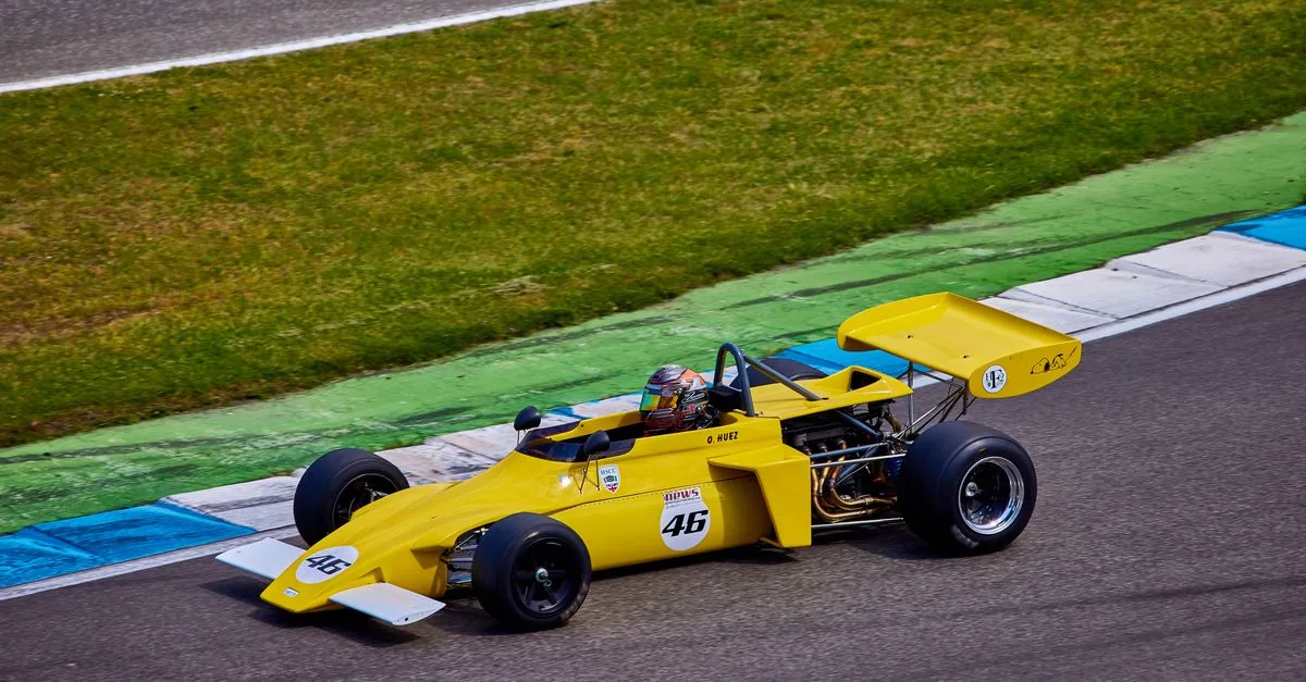 Vibrant yellow vintage race car speeding on a race track, capturing the essence of motorsport.