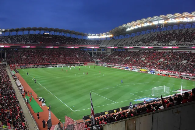 Illuminated football stadium during a night match under bright floodlights.