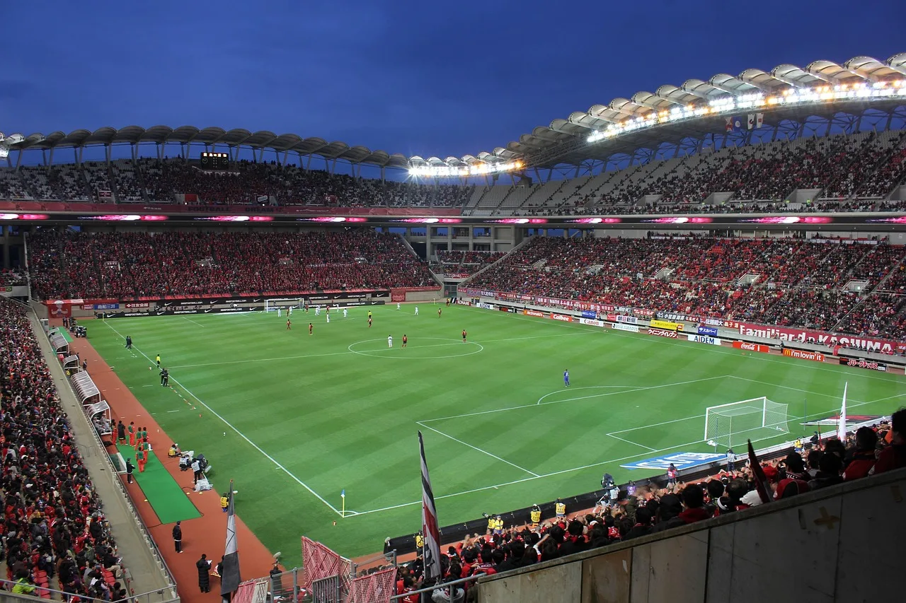 Illuminated football stadium during a night match under bright floodlights.