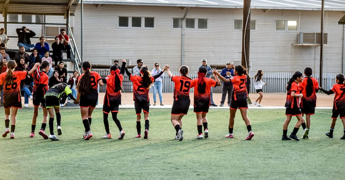 Women's soccer team celebrates victory with fans in stadium.