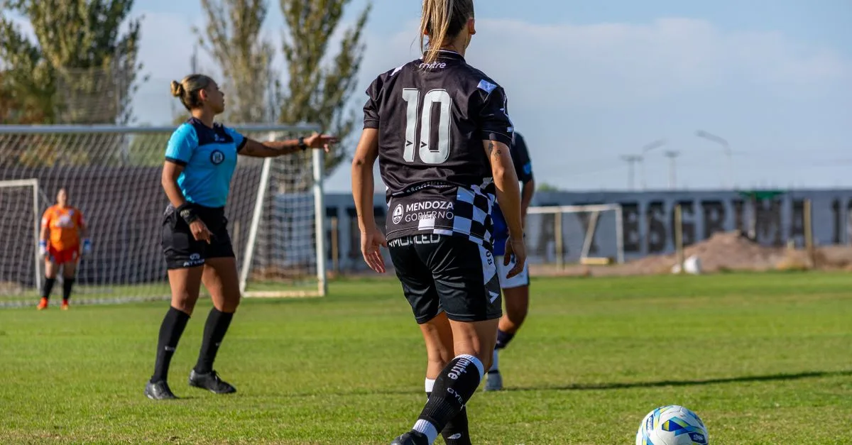 Competitive women's soccer match being played outdoors on a sunny day.