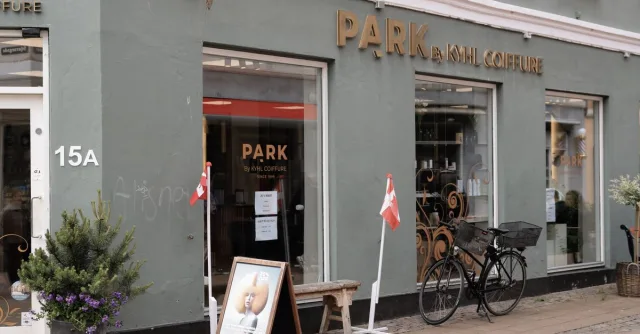 A stylish coiffure shopfront in Copenhagen with a bicycle and Danish flags outside.