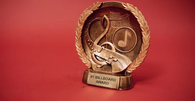 A close-up of a golden music award trophy against a vibrant red background.