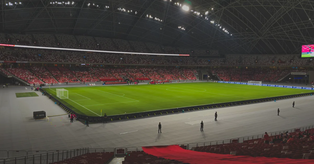 Spacious indoor soccer stadium filled with spectators. Bright lighting enhances the green field.