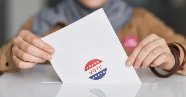 Close-up of hands holding a vote ballot, symbolizing election participation.