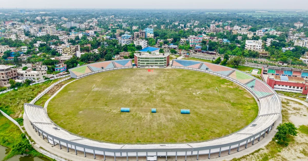 Aerial view of an empty football stadium surrounded by a bustling cityscape.