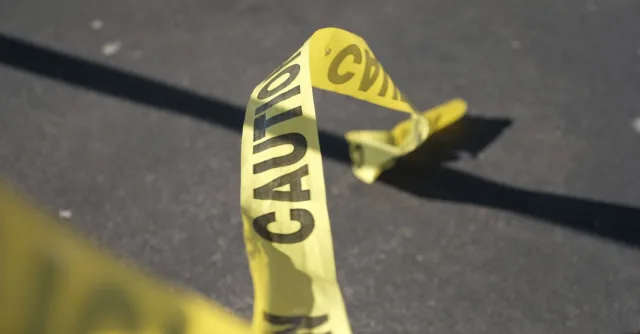 Close-up of yellow caution tape on pavement, suggesting danger or warning.