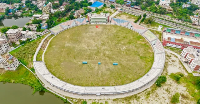 A wide aerial shot of a large empty stadium surrounded by residential buildings.