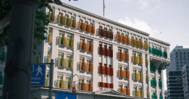 Vibrant multi-colored window shutters on a historical building's facade with urban surroundings.