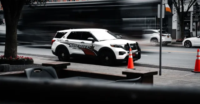 Sheriff's vehicle parked on a bustling city street with traffic motion blur.