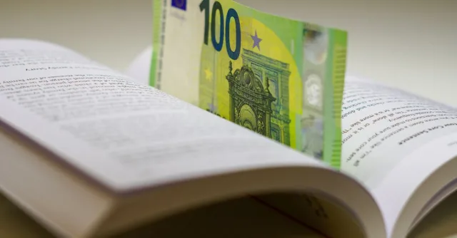 A 100 euro bill used as a bookmark between open pages of a book, symbolizing wealth and knowledge.